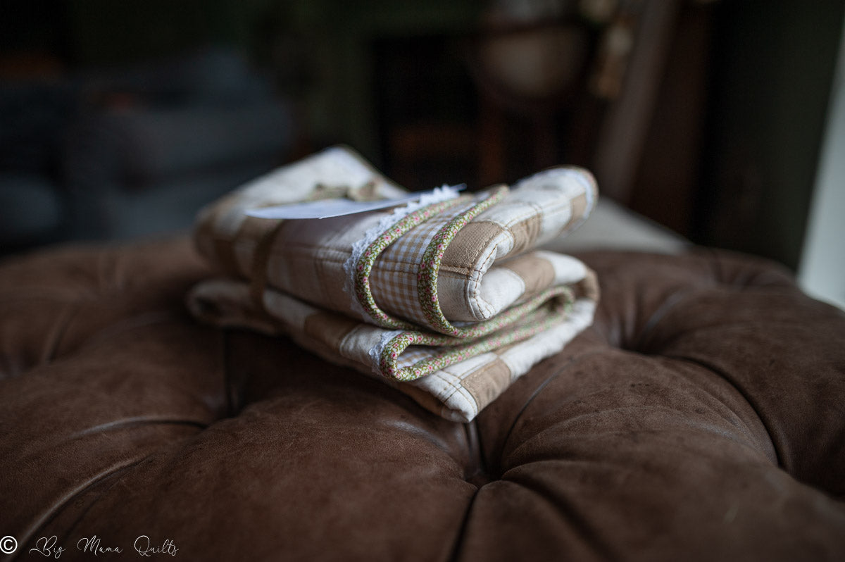Quilt folded on a brown cushion with a blurred background